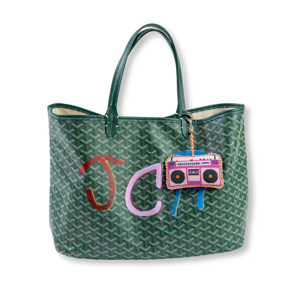 Green patterned tote bag with colorful 'JC' initials and boombox charm on a white background