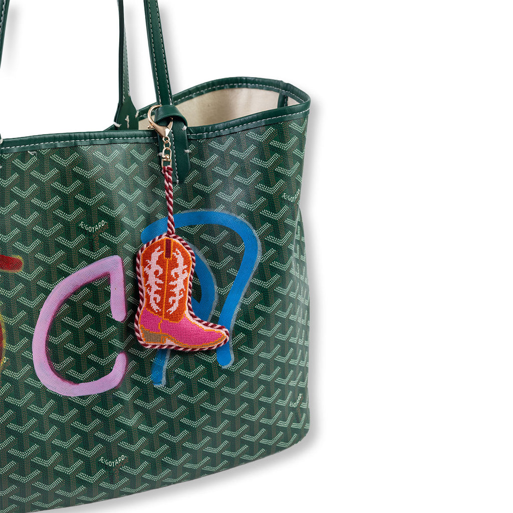 Green patterned handbag with a colorful keychain featuring a boot design on a white background