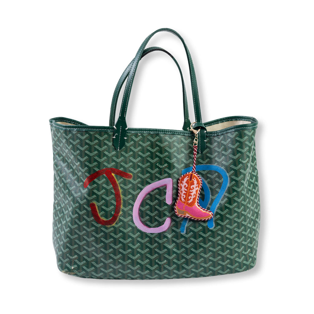 Green patterned handbag with colorful initials and a boot charm on a white background