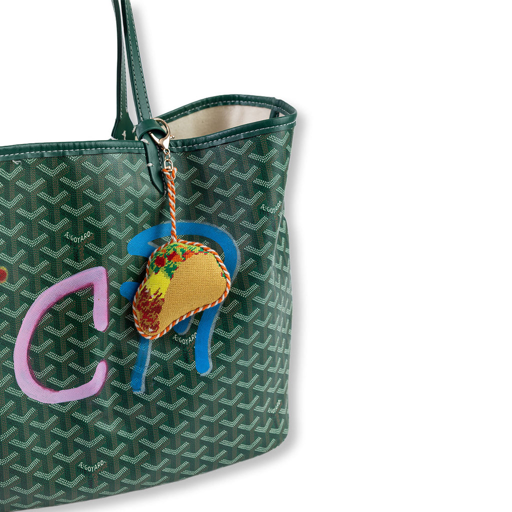 Green patterned handbag with a colorful taco charm on a white background