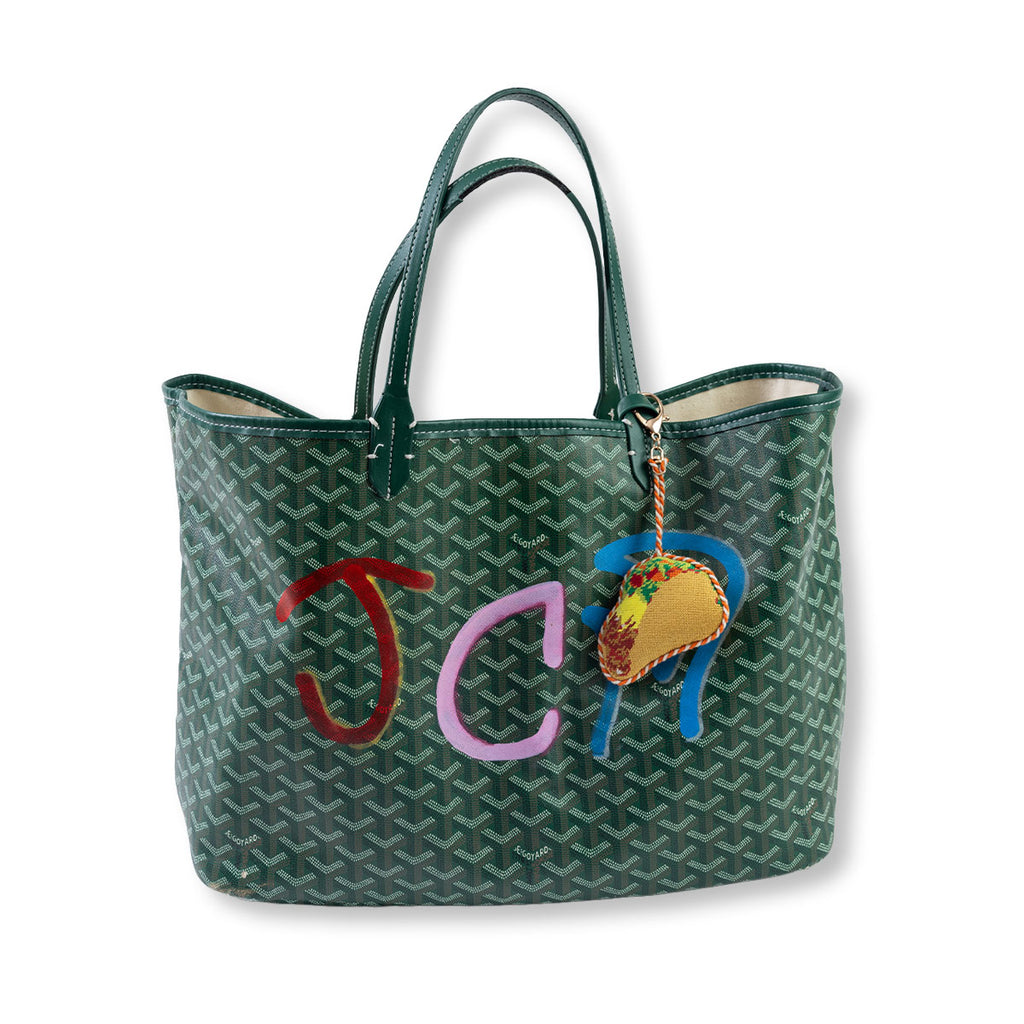 Green patterned handbag with colorful initials and a taco charm on a white background