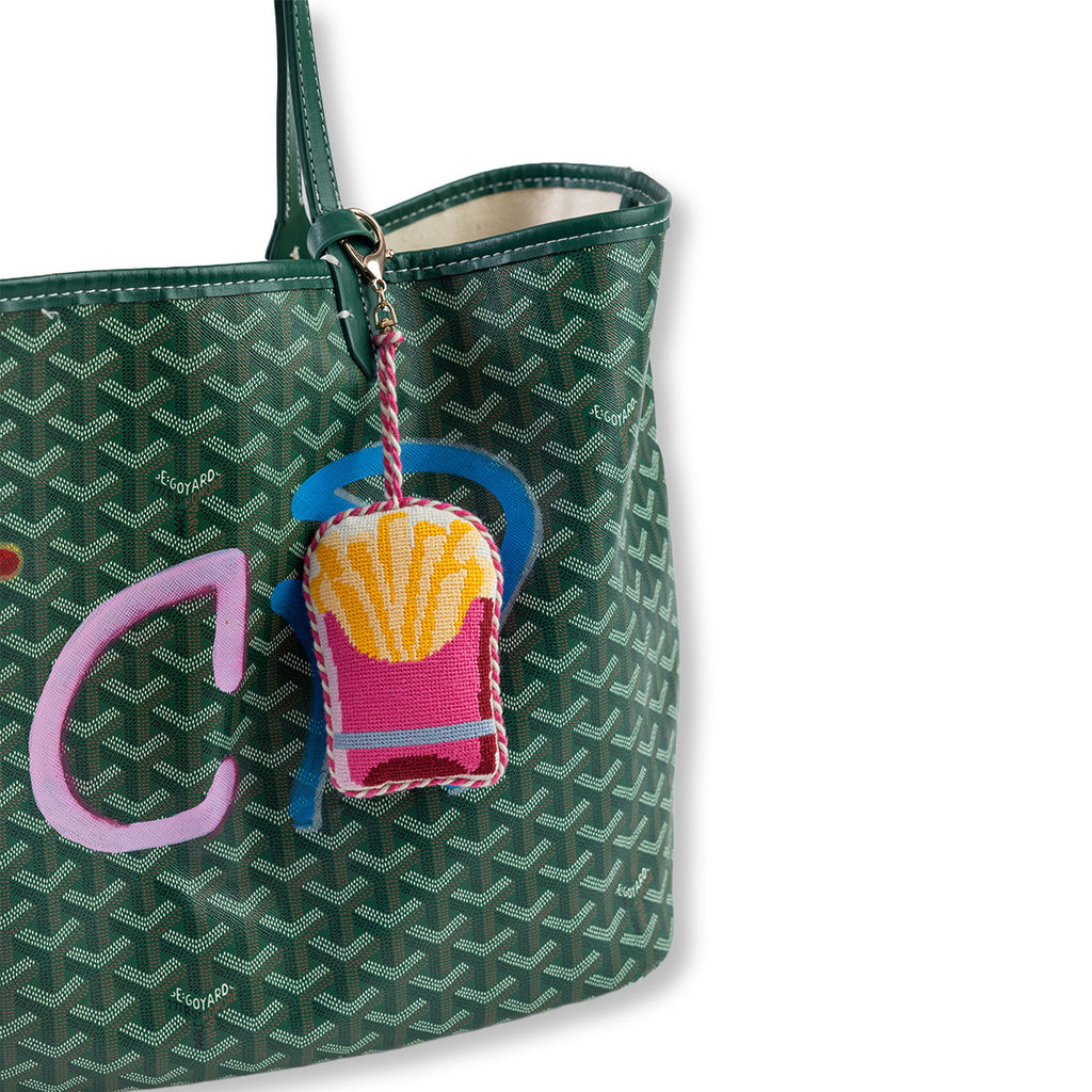 Green patterned handbag with a colorful keychain on a white background