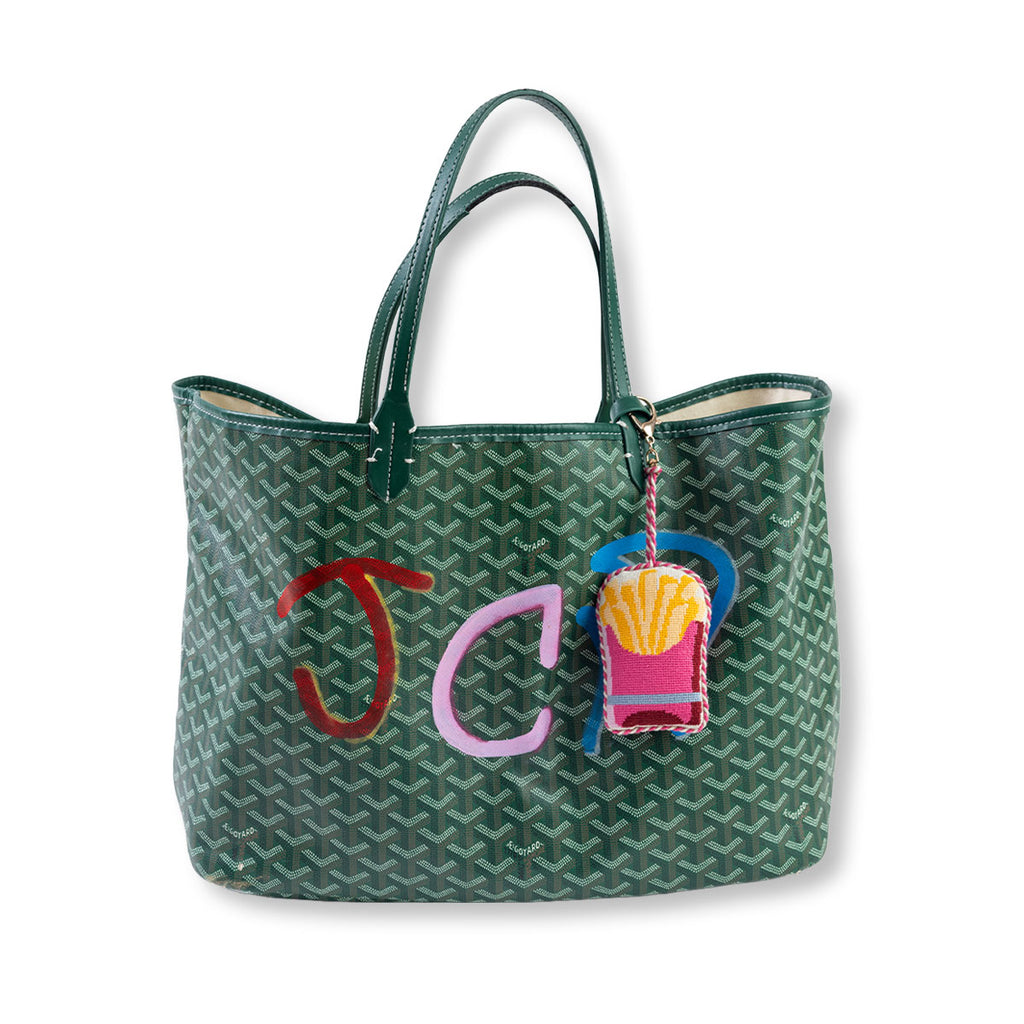 Green patterned tote bag with colorful 'JC' initials and a French fry charm on a white background