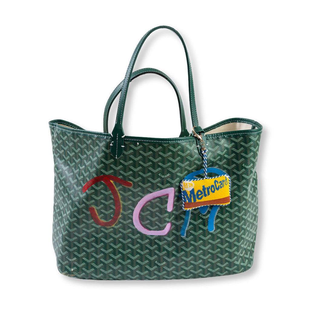 Green patterned tote bag with colorful letters and a MetroCard charm on a white background