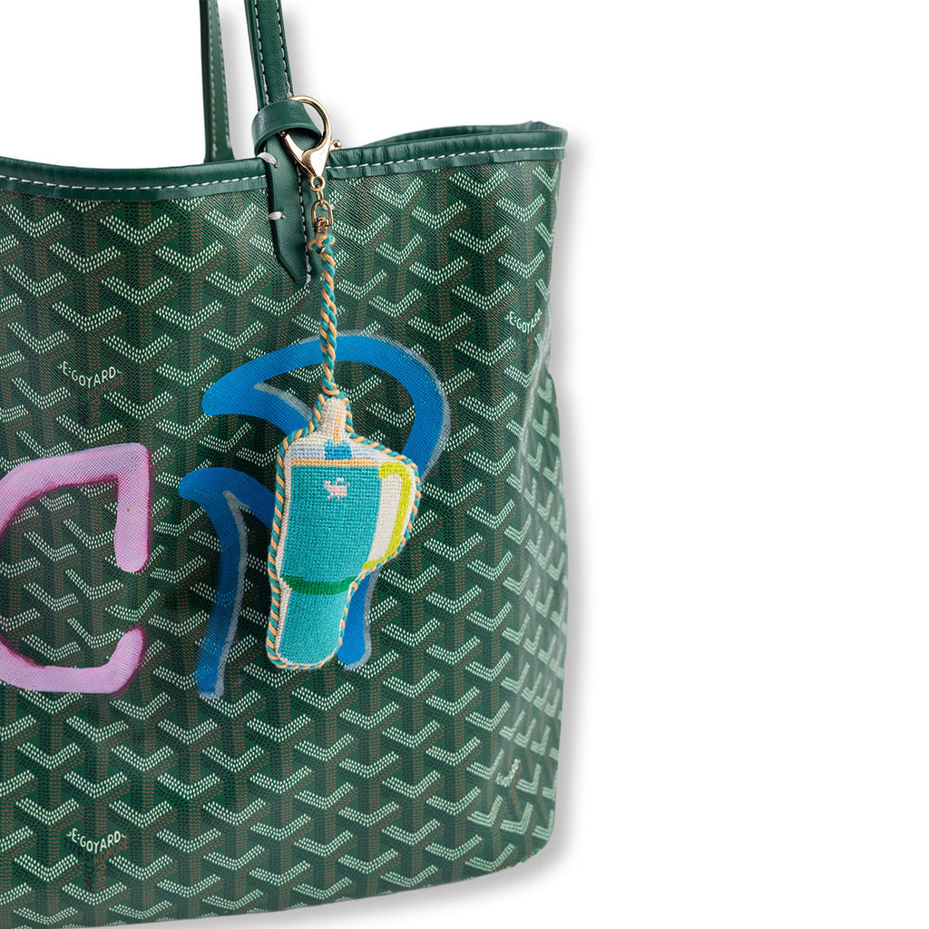 Green patterned handbag with a colorful keychain attached on a white background