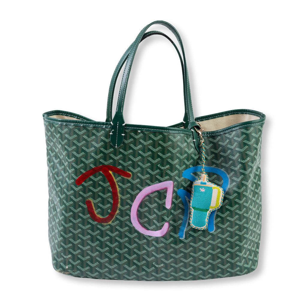 Green patterned handbag with colorful initials and a keychain on a white background