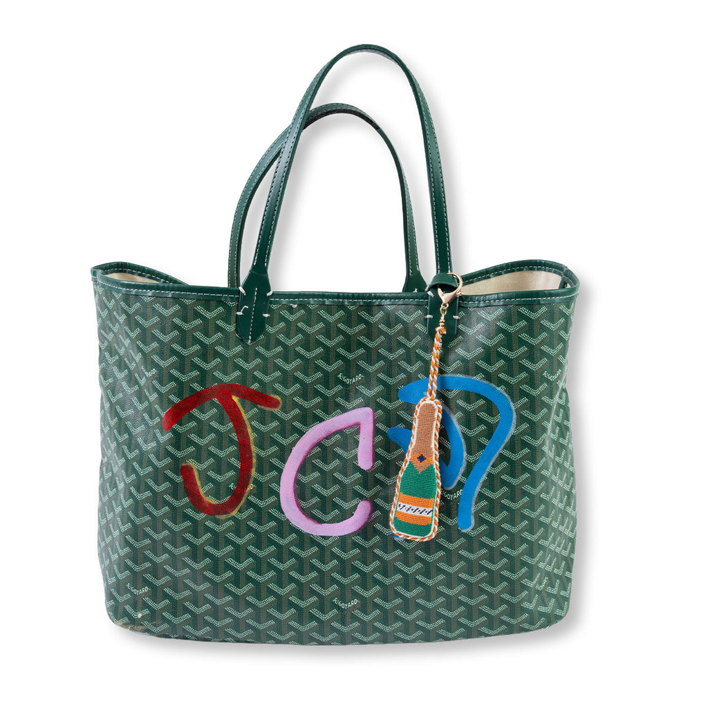 Green patterned handbag with colorful charm on a white background