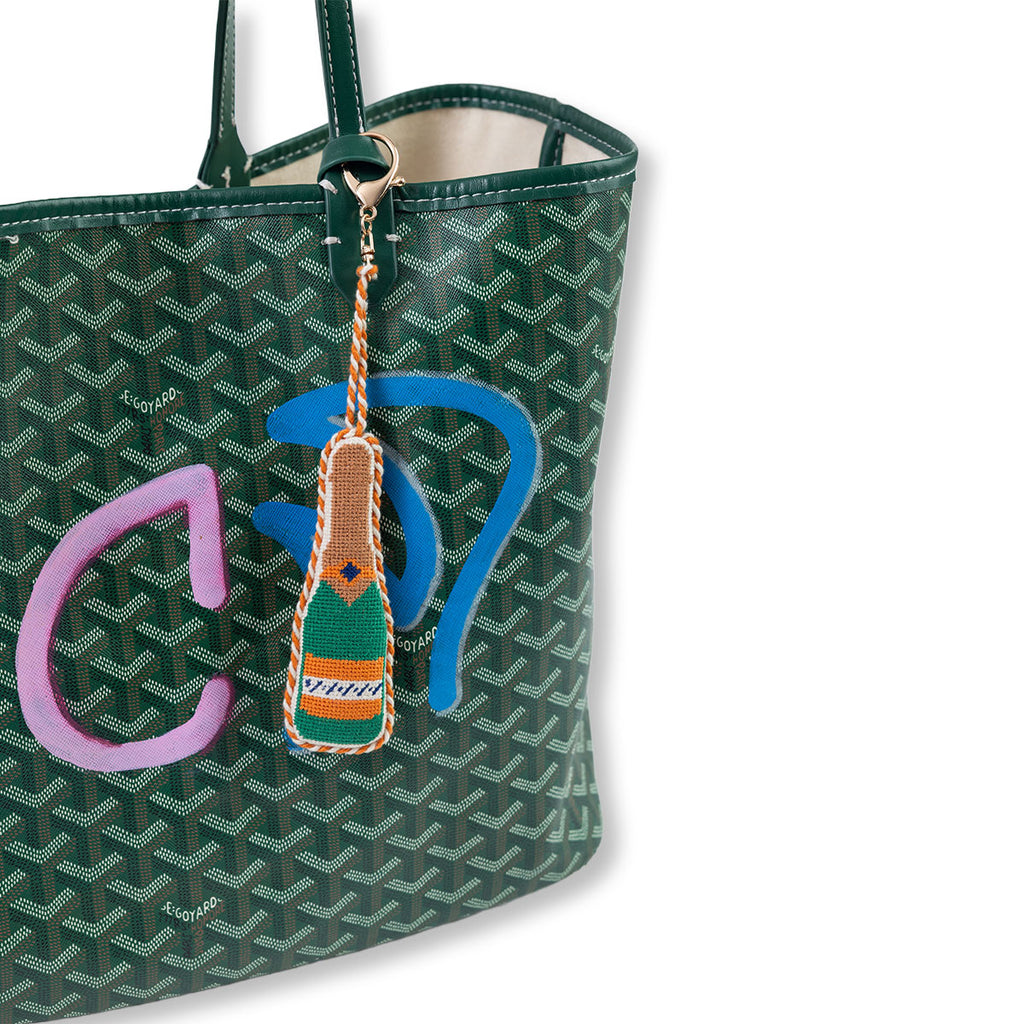 Green patterned handbag with a colorful keychain attached on a white background