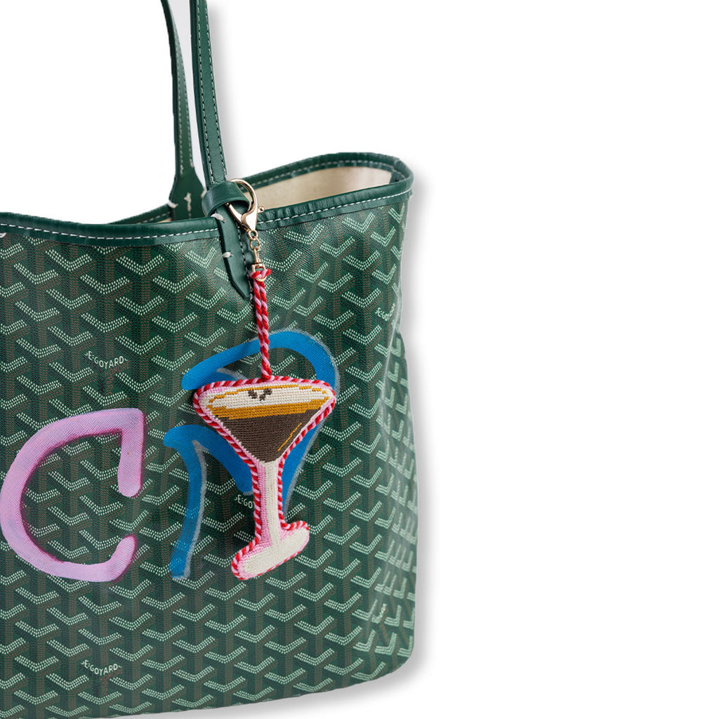 Green patterned handbag with a cocktail charm on a white background