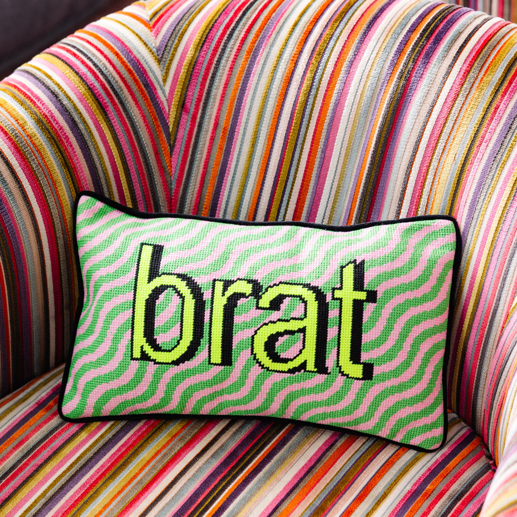Colorful striped chair with a pillow displaying the word 'brat'