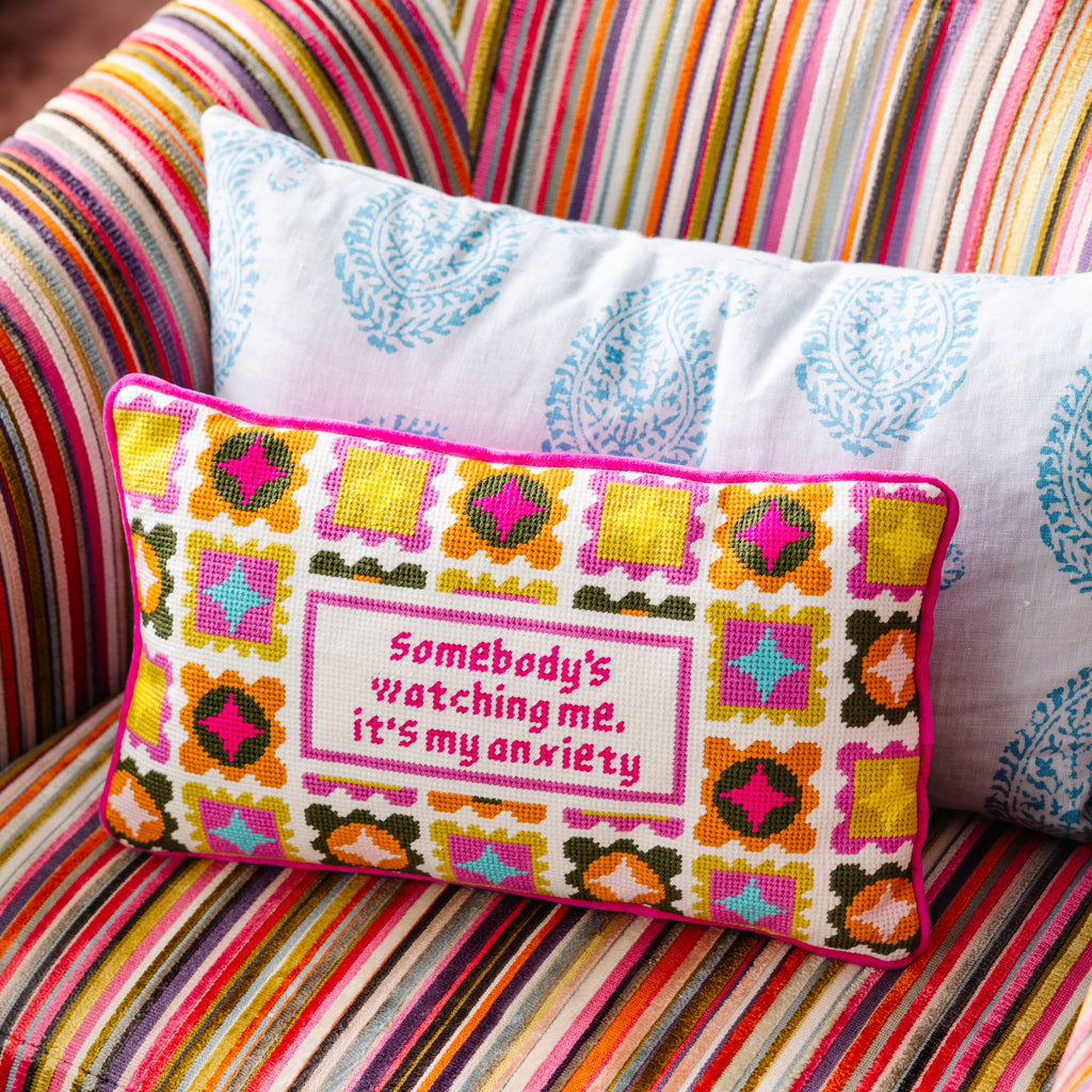 Decorative pillow with colorful pattern and text on a striped couch
