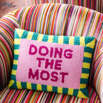 Colorful pillow with 'Doing the Most' text on a striped chair