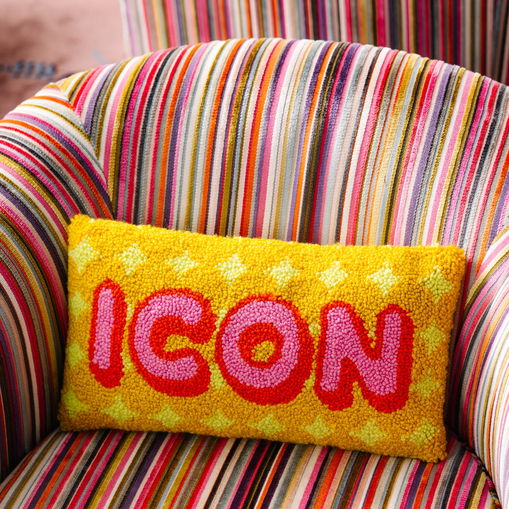 Yellow pillow with 'ICON' text on a multicolored striped chair