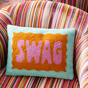 Pillow with 'SWAG' text on a colorful striped chair