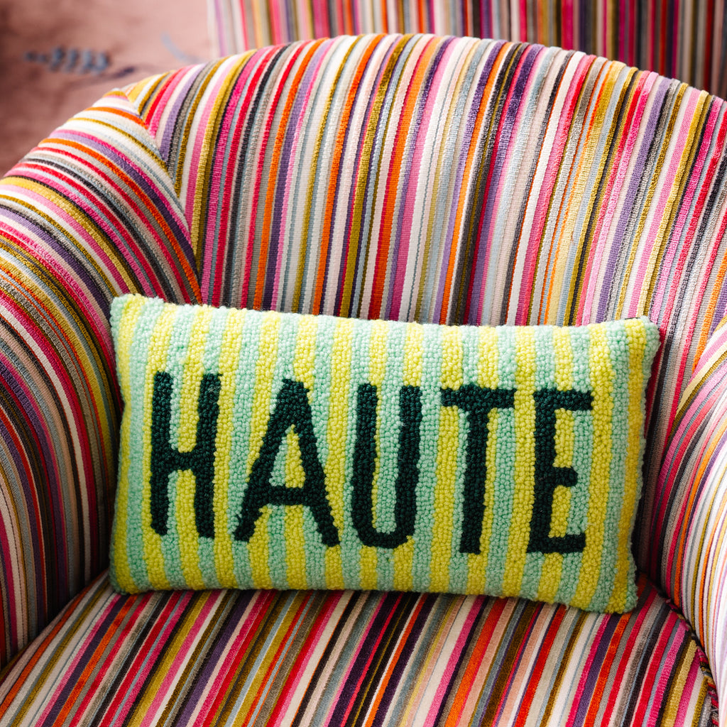 Colorful striped chair with a pillow displaying the word 'HAUTE'.