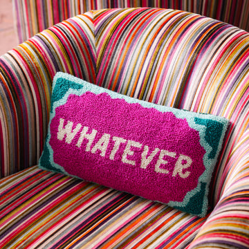 Colorful striped chair with a pillow that says 'Whatever' on a multicolored background