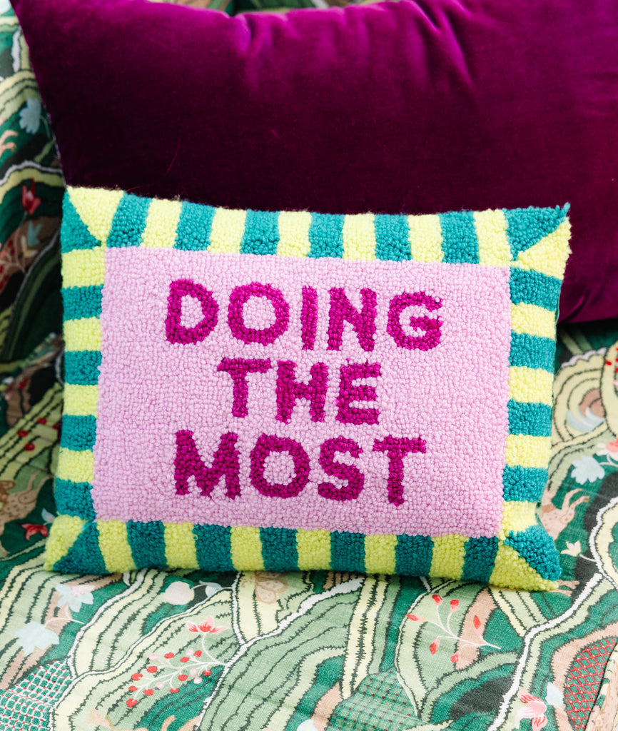 Decorative pillow with 'DOING THE MOST' text on a colorful background