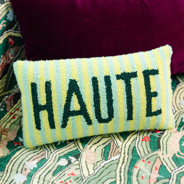 Decorative pillow with 'HAUTE' text on a patterned fabric background