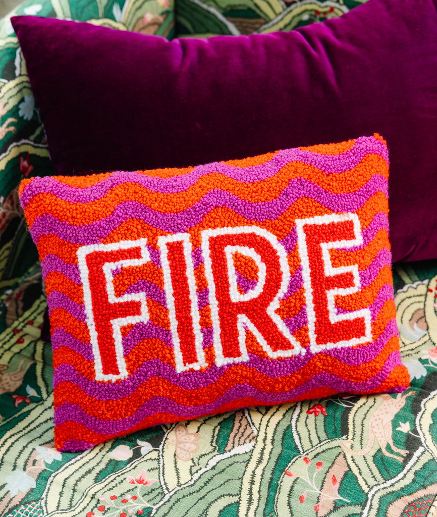 Decorative pillow with 'FIRE' text on a colorful patterned fabric background