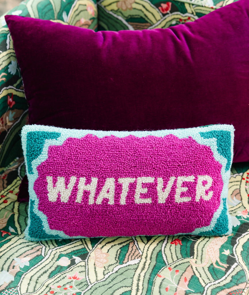 Decorative pillow with 'WHATEVER' text on a patterned surface