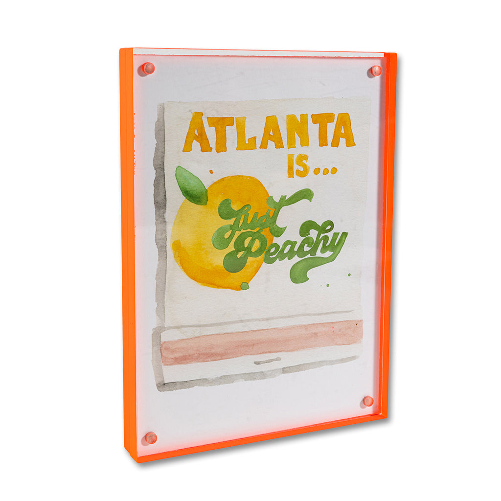 Atlanta Matchbook - Furbish Studio, Atlanta matchbook watercolor print with a yellow peach fruit paint under the saying "Atlanta is... Just Peachy" enclosed in a 5" x 7" orange magnetic acrylic floating frame