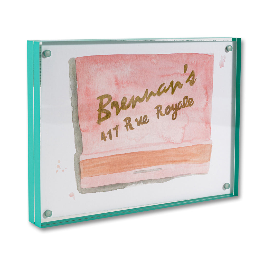 Brennan's Matchbook - Furbish Studio, A matchbook watercolor print with gold painted "Brennan's 417 Rue Royal" saying and a peach background color enclosed in a 5" x 7" mint-green magnetic acrylic floating frame facing a side view
