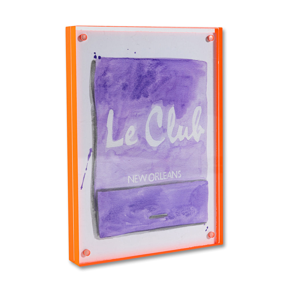 Le Club Matchbook - Furbish Studio, Le Club New Orleans matchbook watercolor print with a lavender background paint and the "Le Club New Orleans" is painted in white in the middle enclosed in a 5" x 7" orange magnetic acrylic floating frame facing a side view