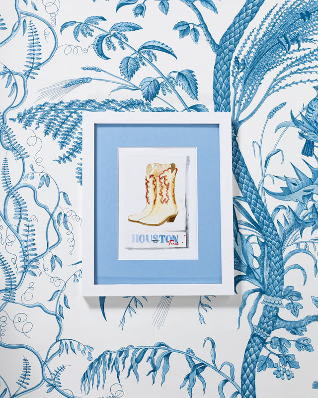 Houston Matchbook - Furbish Studio, A Houston Texas matchbook watercolor print illustrating a pair of boots painted in brown and topaz shades with a white background color and the Title "Houston Texas" at the bottom is painted in blue and red in a white 9x12 frame attached to the wall