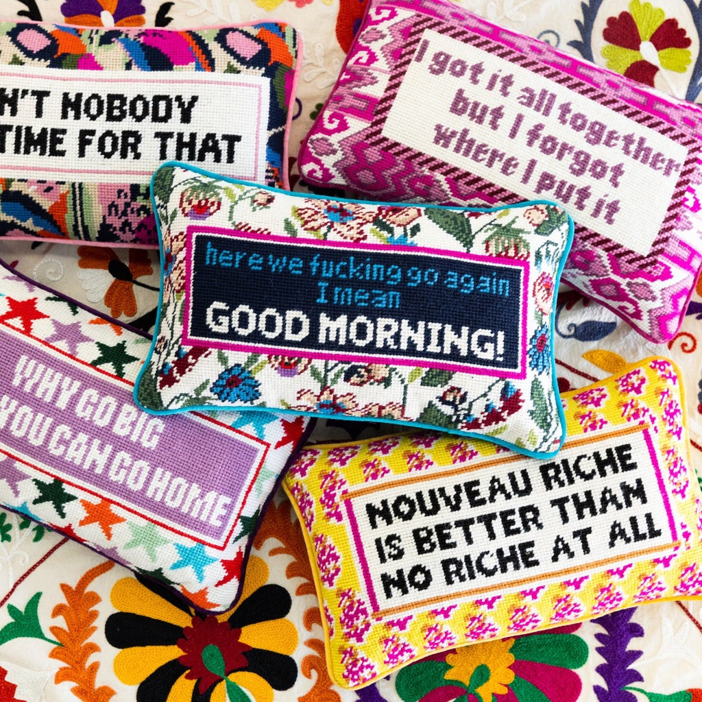 hand embroidered in wool and backed in luxe blue green velvet chic needlepoint pillow with "here we fucking go again, I mean Good morning!" cheeky saying in front while in the middle of 4 colorful needlepoint pillows