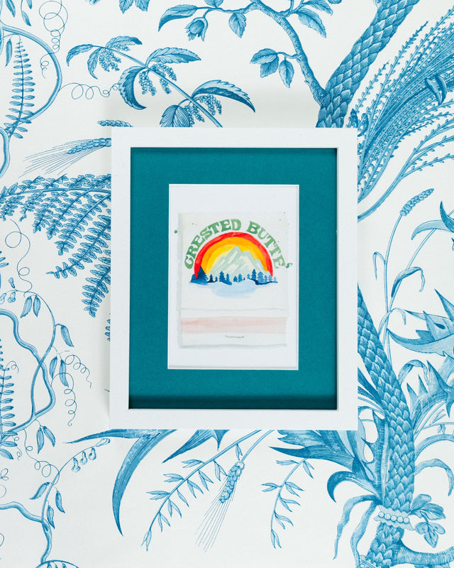 Crested Butte Matchbook - Furbish Studio, A matchbook watercolor print illustrating the Crested Butte Ski Resort's surroundings through a watercolor paint and it is below the dark green painted "Crested Butte" in a 5x7 white frame with a wallpaper background