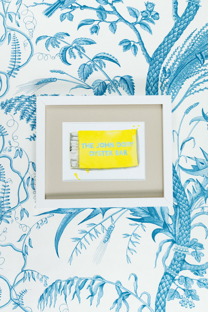 John Dory Oyster Bar Matchbook - Furbish Studio, "The John Dory Oyster Bar" matchbook watercolor print illustrating an opened yellow matchbox positioned horizontally with a light blue paint written "THE JOHN DORY OYSTER BAR" in a 5x7 white frame with a wallpaper background