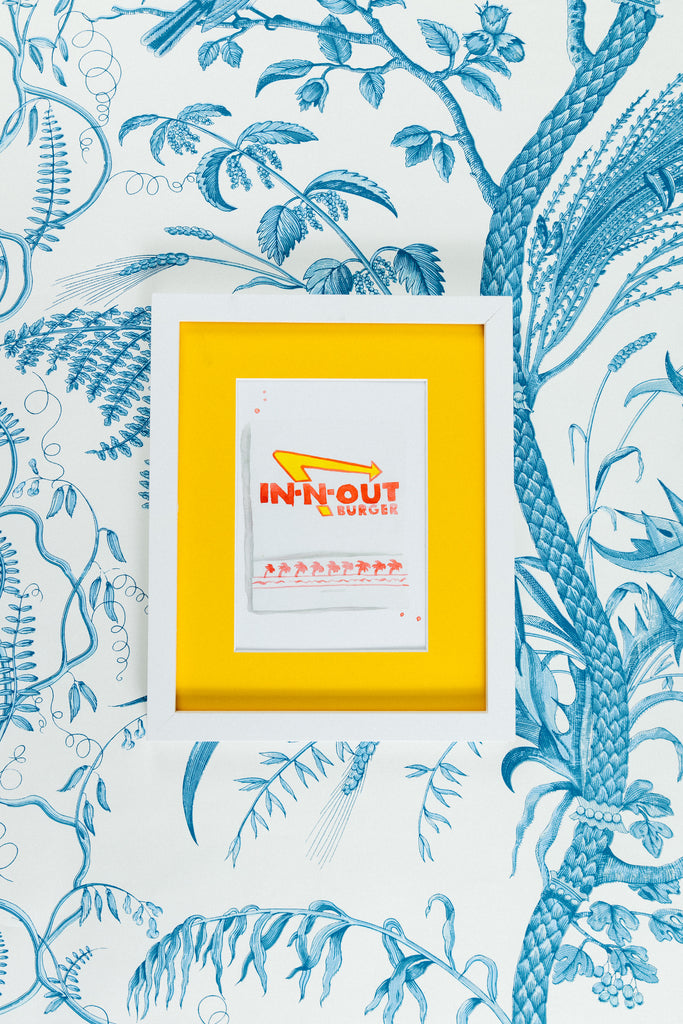 In-N-Out Matchbook - Furbish Studio, An In-N-Out matchbook watercolor print with the restaurant's logo design painted in red and yellow and some palm trees underneath in a 5x7 white frame with a wallpaper background