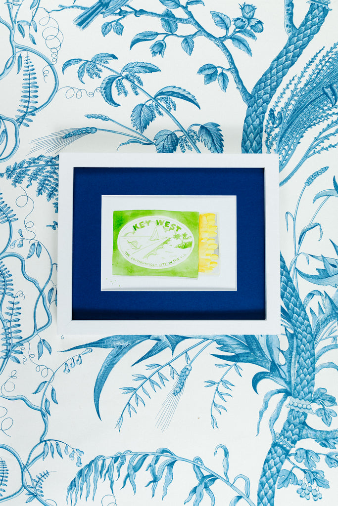 Key West Matchbook - Furbish Studio, Key West matchbook illustrating an opened matchbox painting and the Island's scenery painted with a yellow green shade in a 5x7 white frame with wallpaper background