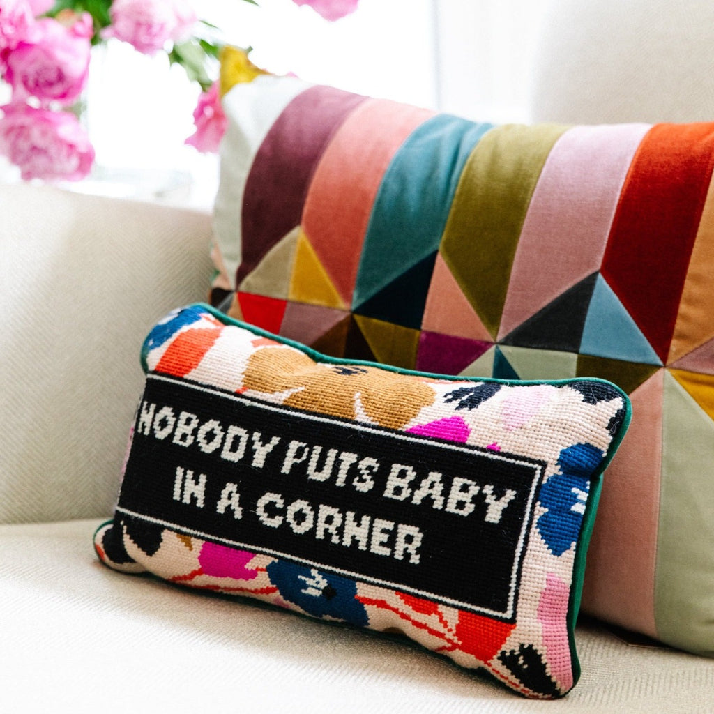 Baby in the Corner Needlepoint Pillow - Furbish Studio, luxe green velvet charming-meets-chic hand needlepoint pillow with a "Nobody puts baby in a corner" saying sitting on a coach with a colorful pillow