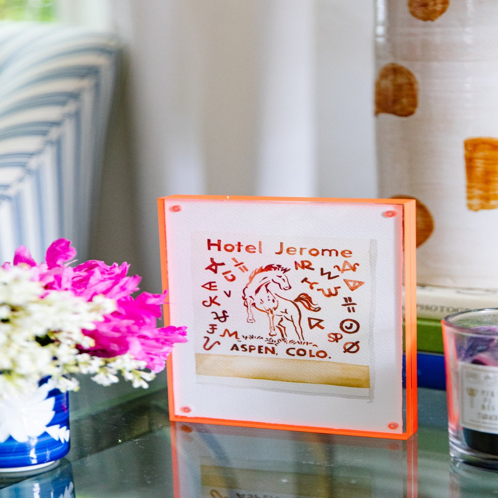 Hotel Jerome Matchbook - Furbish Studio, A Hotel Jerome matchbook watercolor print with a horse, symbols and the Title "Hotel Jerome" and "Aspen Colo" painted in brown with an off-white background color enclosed in a 5" x 7" orange magnetic acrylic floating frame facing a side view