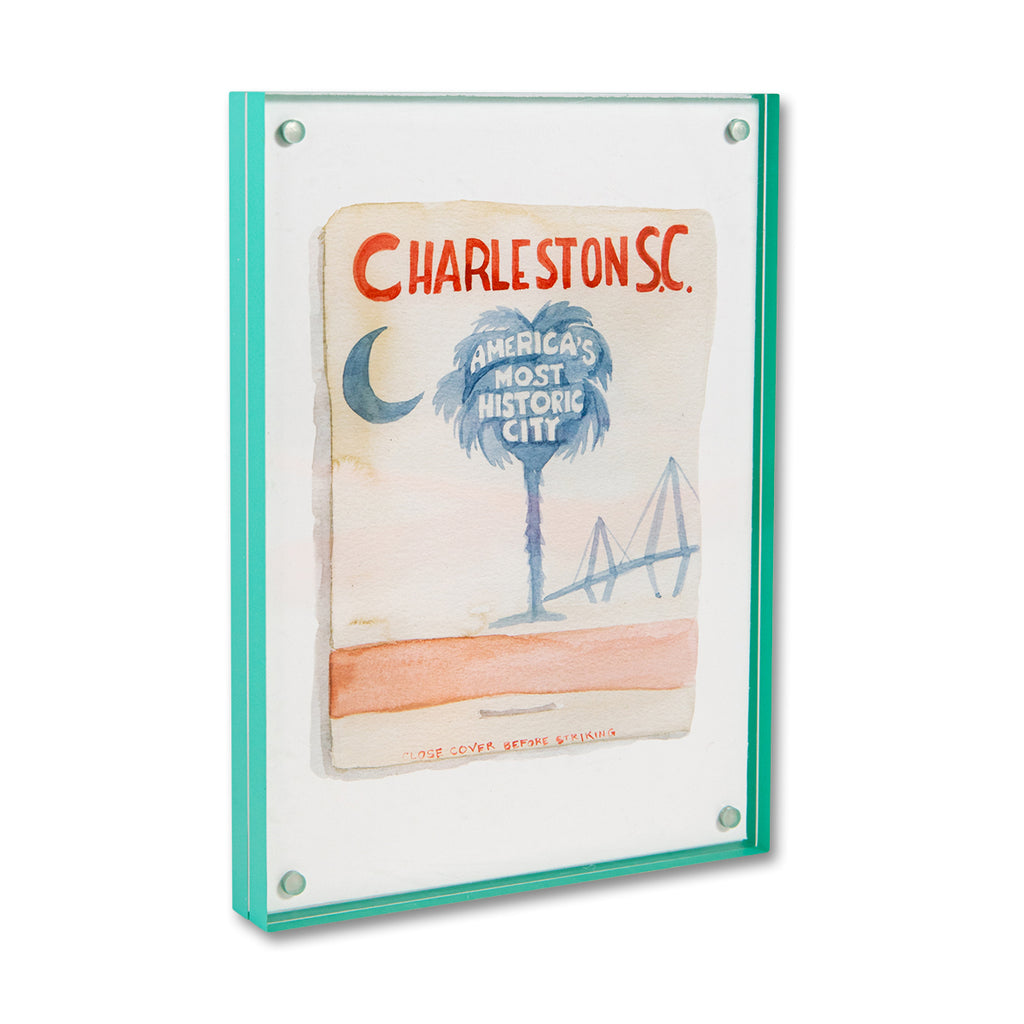 Charleston Matchbook - Furbish Studio, Charleston SC matchbook watercolor print illustrating Charleston's surroundings which are the palm tree and Arthur Ravenel Jr. Bridge in the background enclosed in a 5" x 7" mint-green magnetic acrylic floating frame facing a side view