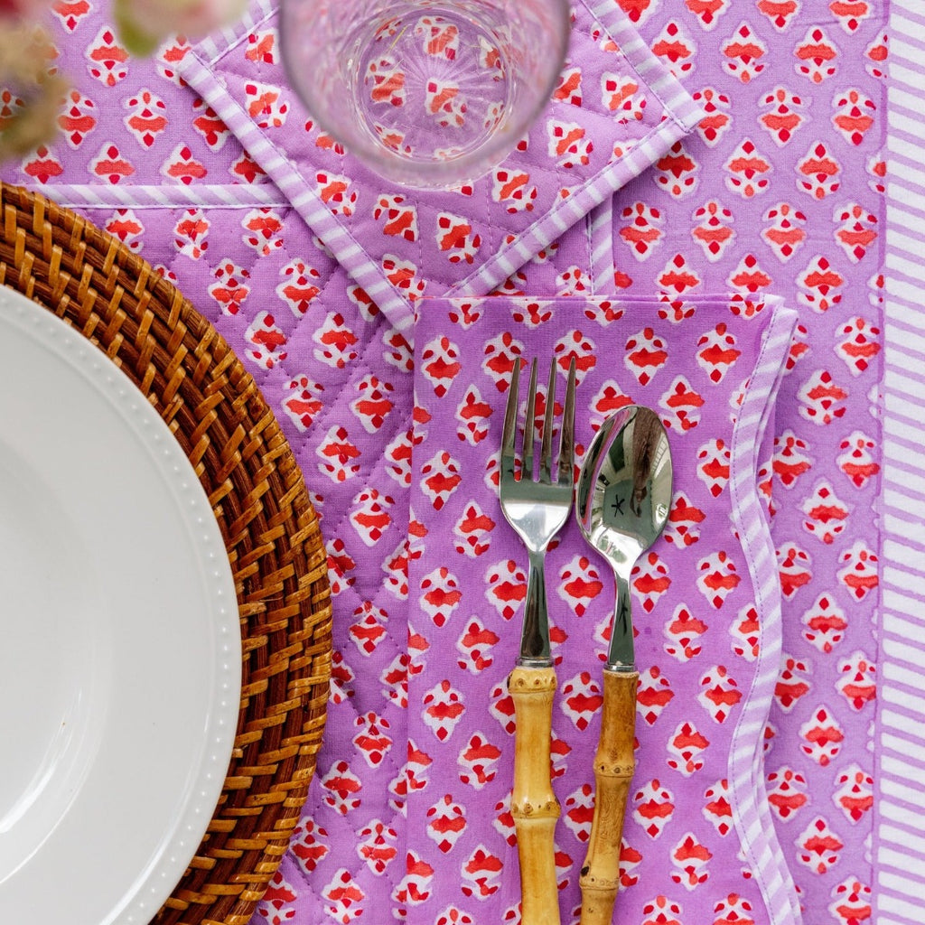 a beautiful table setting showcasing Ambroeus table linens with a spoon and fork positioned to the right of the plate, a glass above the silverware and a table cloth beneath all of them